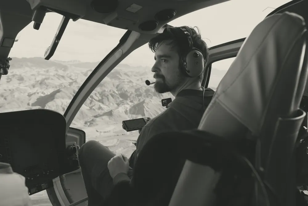 Austin Wood filming from the front seat of a helicopter, in black and white