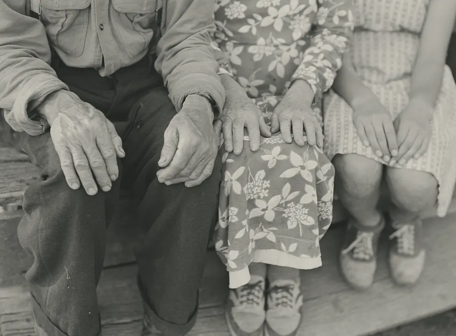 The hands of an older couple and their granddaughter, resting on their knees